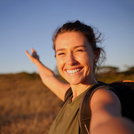 Smiling Woman Backpacking In Nature During Golden Hour