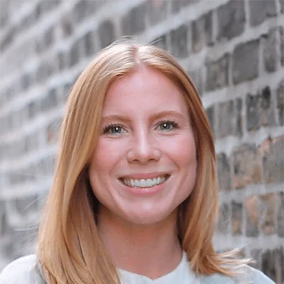 Doctor of Naturopathic Medicine Ashley Woyak Smiling In Front Of Brick Wall