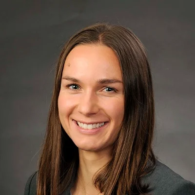 Doctor of Physical Therapy Sam Blum Smiling In Front Of Grey Background